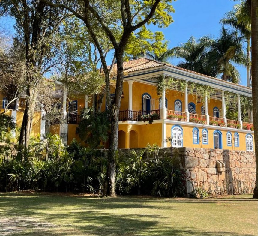 Fachada amarela do casarão da Fazenda Santa Maria entre árvores